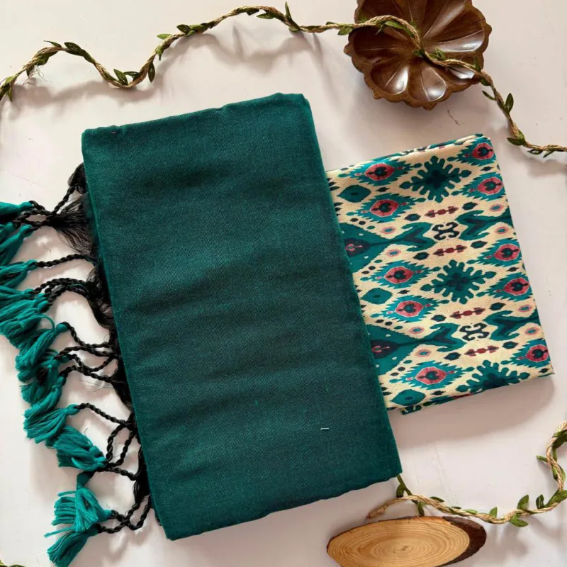 A folded teal saree with tasselled ends beside its printed blouse piece