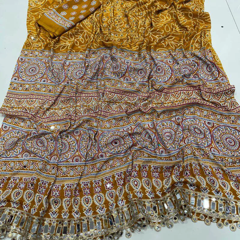 A mustard printed saree with a mirror-work border, spread out