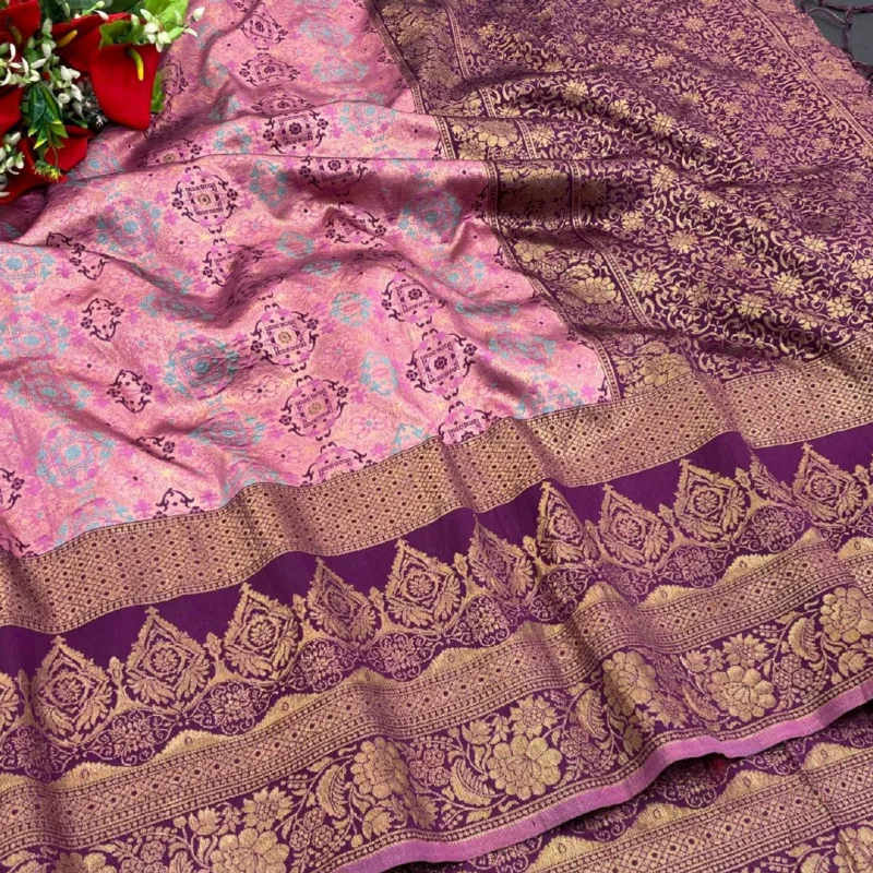 A pink silk saree with a broad purple border woven in gold, spread out